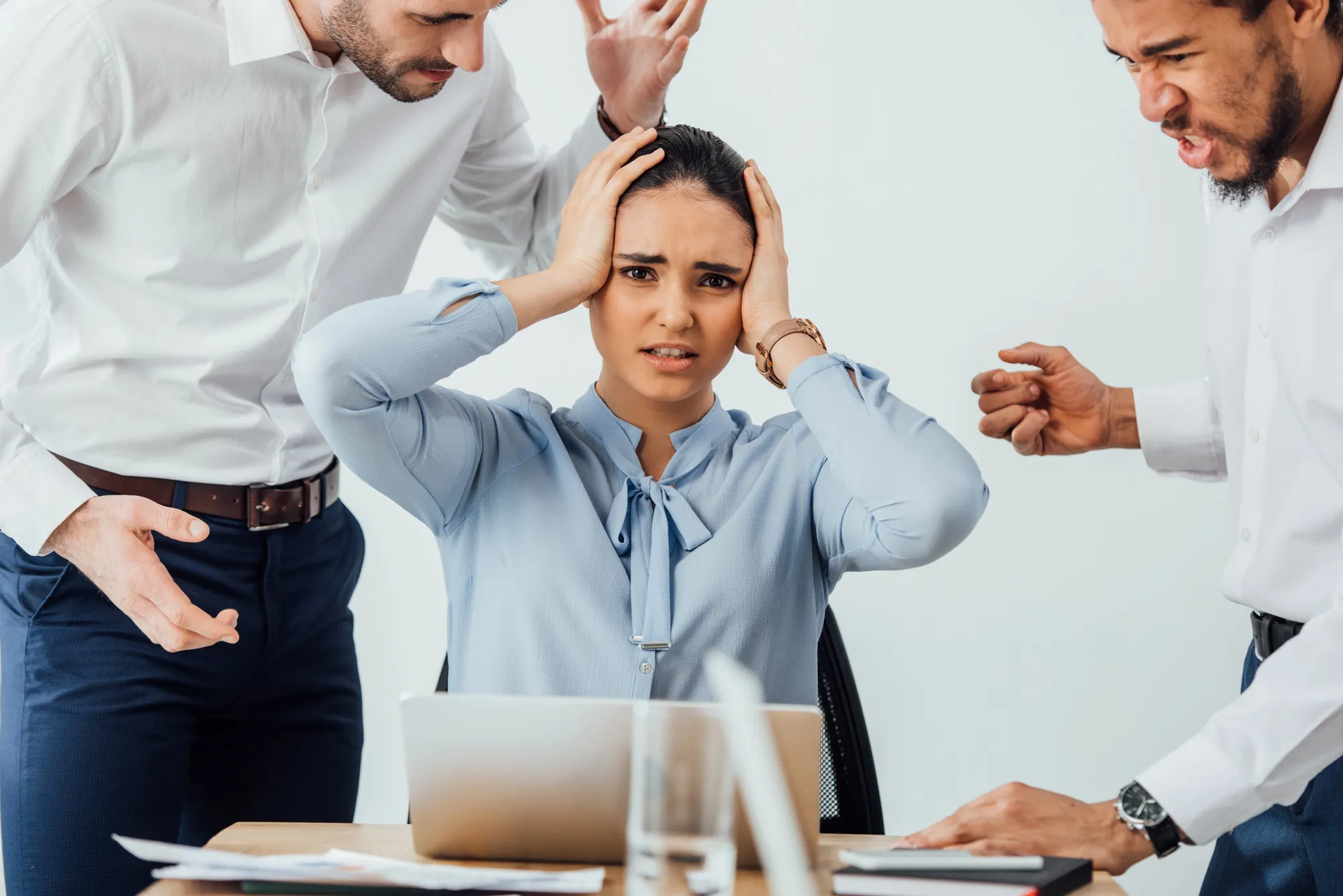 Selective focus of angry multiethnic businessmen quarreling at offended mexican colleague in office